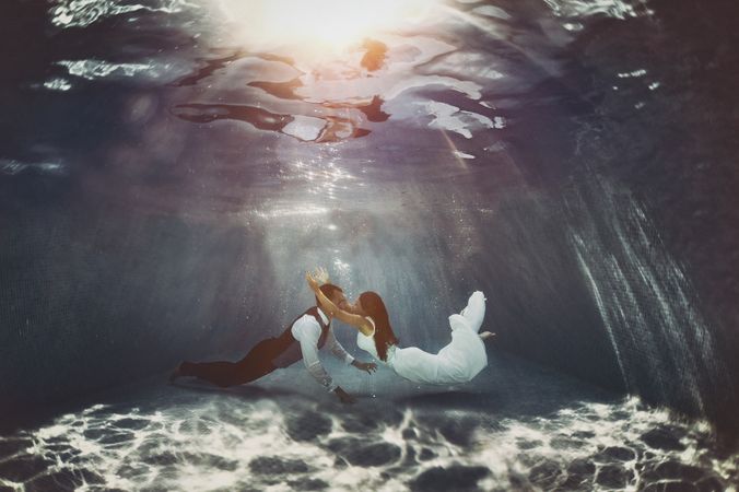 Bride and groom swimming underwater