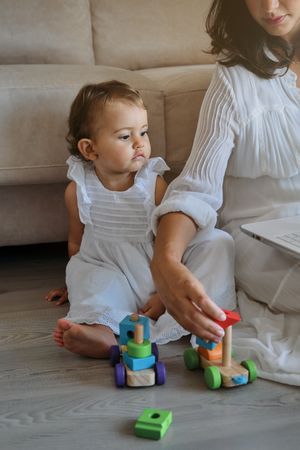 Crop mom playing with baby on floor at home