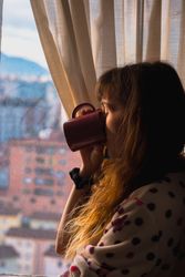Woman enjoying hot beverage near fridge