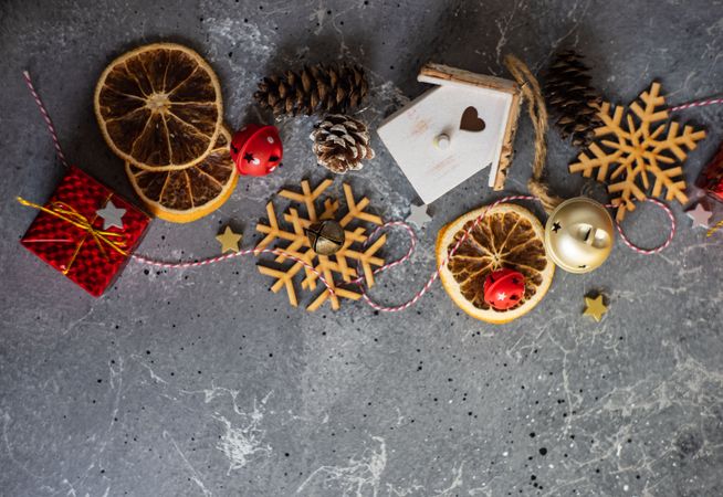 Top view of wooden snowflakes, gift boxes, dried orange slices and pine cones on marble table