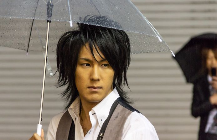Japan - May, 10 2013: Asian man with umbrella looking away