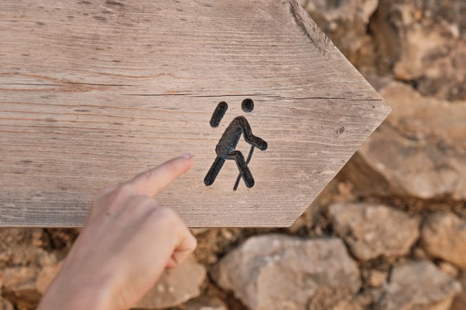 Crop person pointing at pictograph on signboard