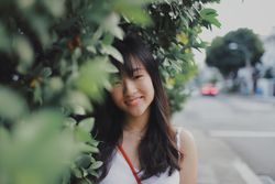 Portrait of woman standing beside tree at daytime