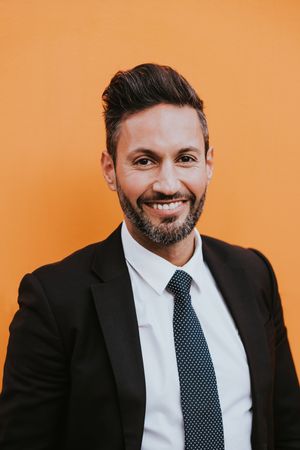 Adult stylish man in costume near orange wall