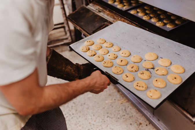 Bald baker checking pastry inside oven