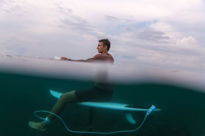 Man sitting on surf board floating in blue water