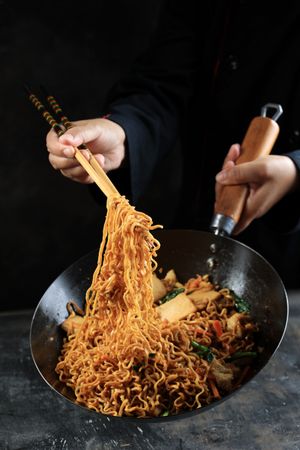 Chef Cooking Chinese Fried Noodle in the Wok using Chopstick