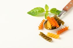 Spoon with color pasta on plain background, space for text and closeup