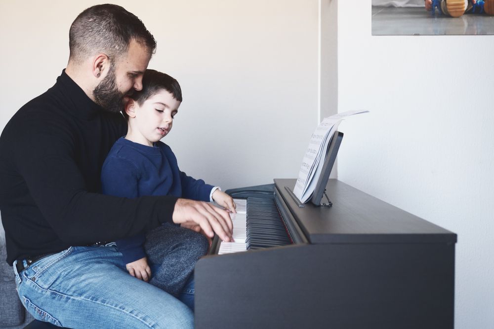 Father teaching son to play piano