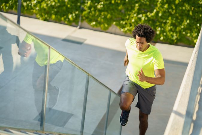 Fit man in neon T-shirt jogging up stairs