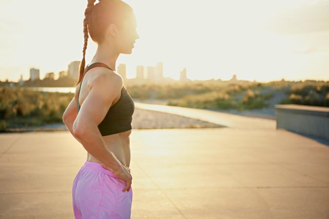 Athletic woman with hands on hips in morning sun before work out