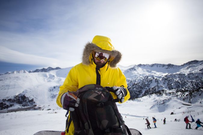 Man on mountain in yellow parka with backpack