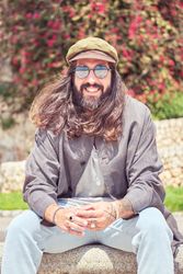 Smiling man sitting on stone border