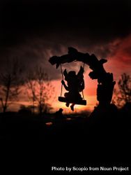 Silhouette of child riding swing during sunset bE8oM4