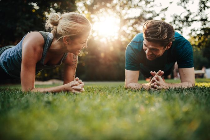 Smiling couple doing core workout on grass
