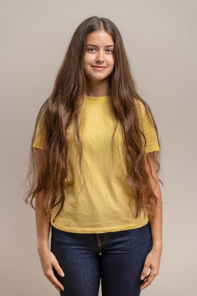Simple front view portrait of a young woman in a plain yellow t-shirt.