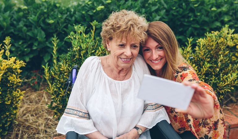 Daughter taking selfie with her mother in wheelchair