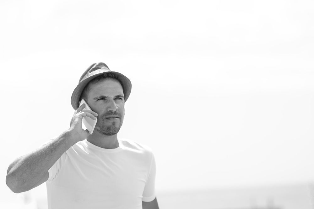 Monochrome shot of male speaking on phone outside