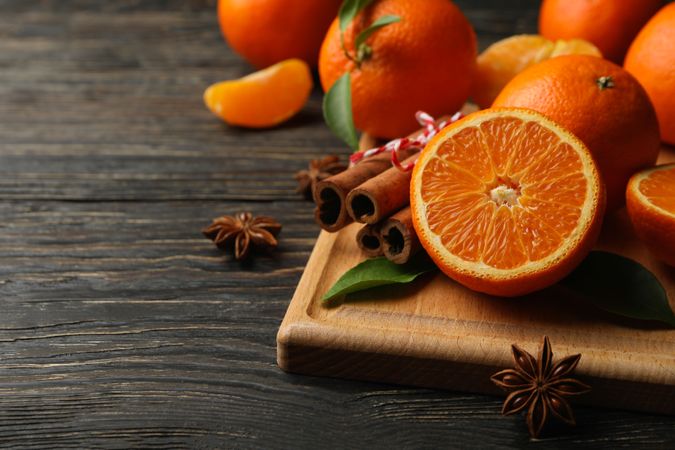 Board with mandarins and cinnamon on wooden background