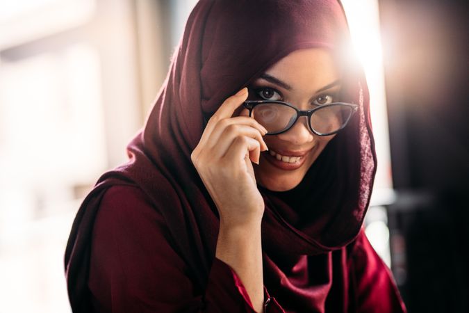 Close up of muslim woman in hijab peeking over her eyeglasses