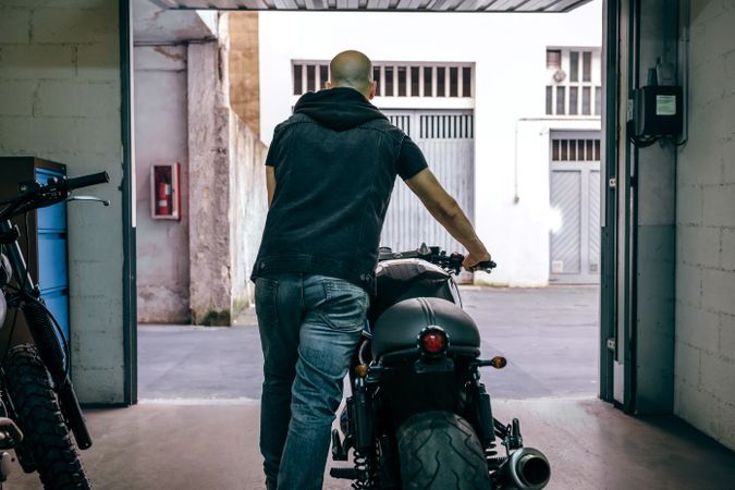 Man with custom motorbike leaving the garage