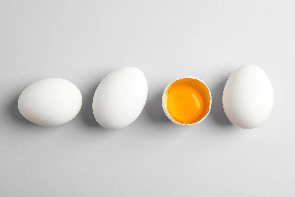 Chicken eggs and half with yolk on light background, space for text