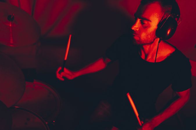 Man with drumsticks playing on drums in redness