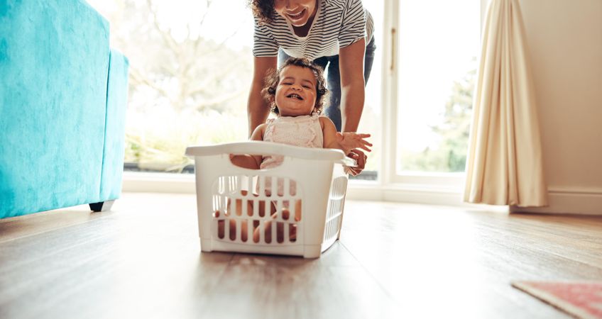 Baby sitting in a plastic basket being pushed by mother