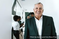 Portrait of businessman looking at camera and smiling with his team in background 4NQ895