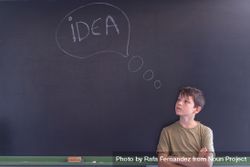 Boy standing at board with "idea" in thought bubble written in chalk 4OgRo4