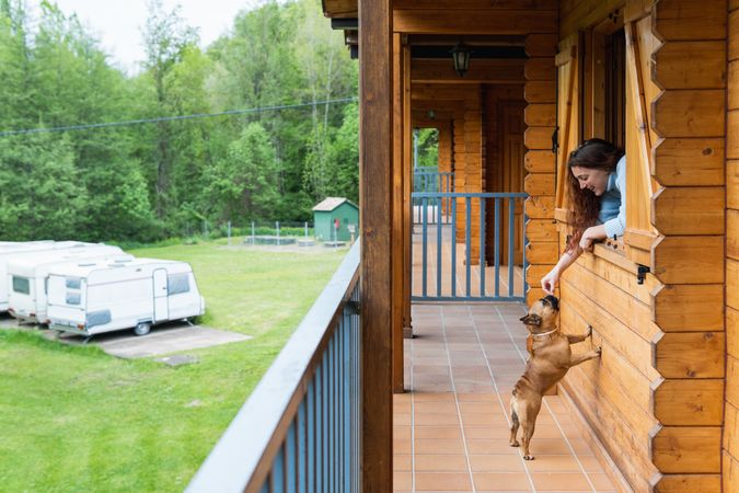 Woman looking at cute dog on terrace of house