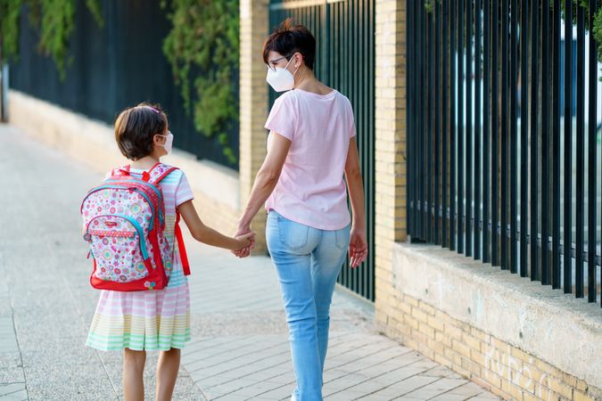 Woman and girl walking to school in face masks