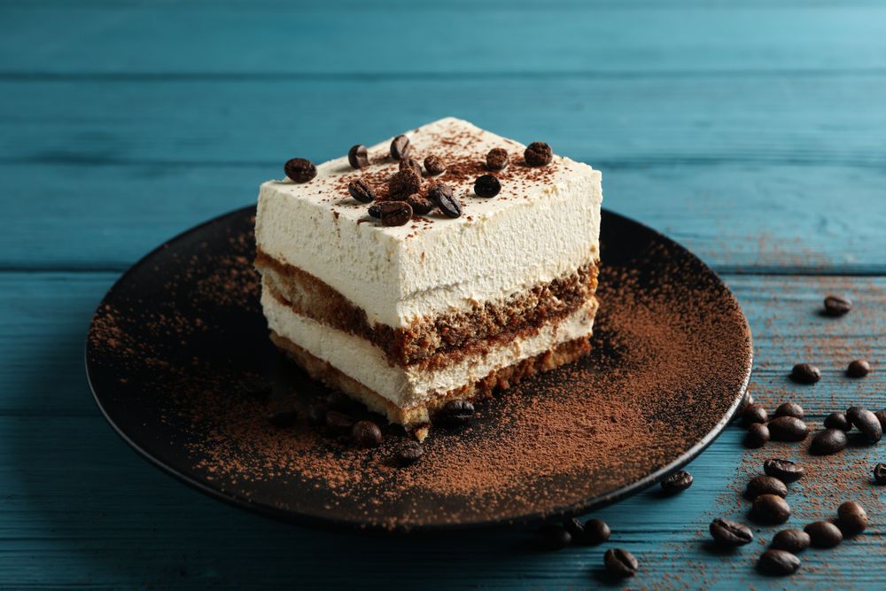 Plate with tiramisu on wooden background. Tasty dessert