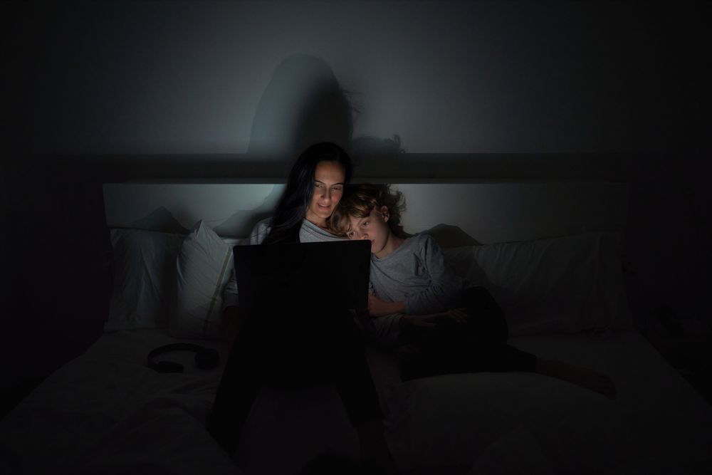 Mother with son doing homework in darkness