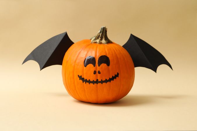 Pumpkins with smile and wings on beige background
