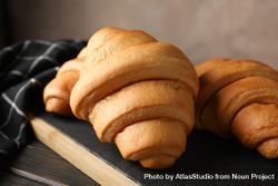 Board with croissants on wooden table with towel, close up bxJld5