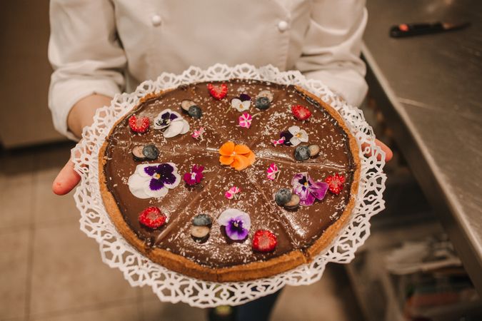 Brown pie decorated with flowers in woman hands