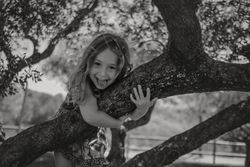 Smiling girl climbing tree in sunny day