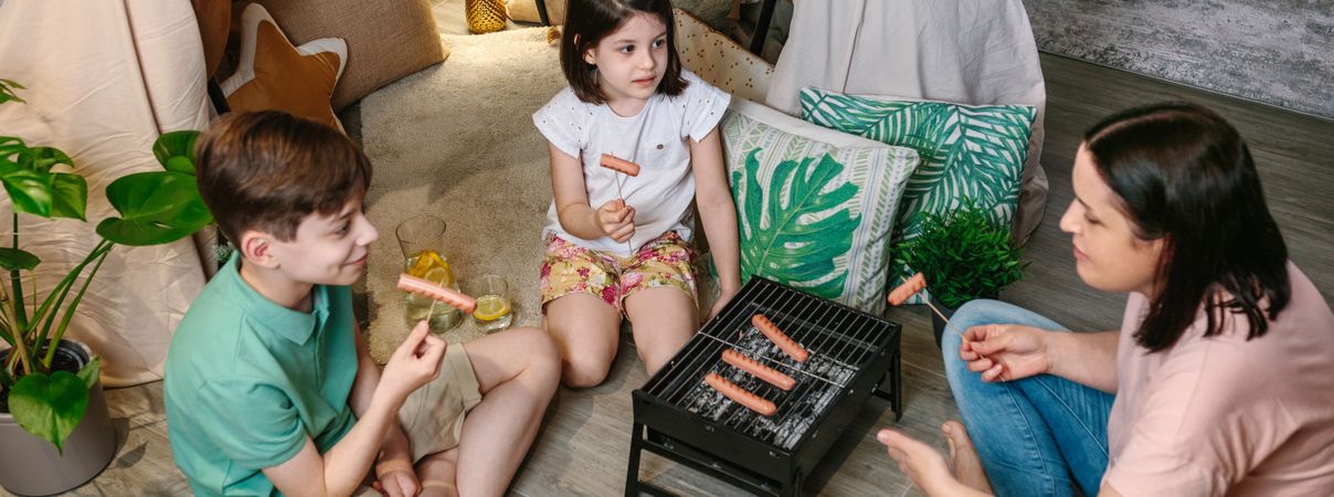 Top view of family grilling and eating sausages on barbecue