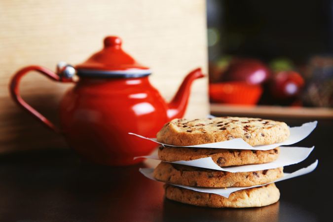 Pile of cookies on kitchen counter with red tea pot