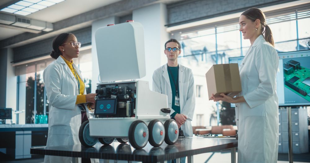 Diverse Team of Industrial Specialists Working on Remotely Controlled Robot, Using a Laptop.