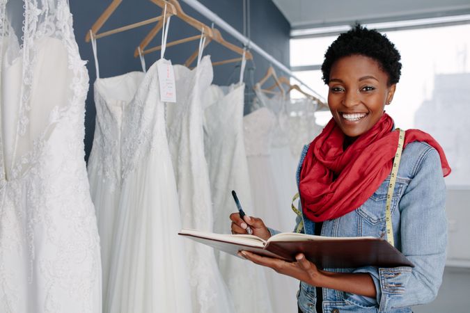 Portrait of smiling female bridal store owner with a journal