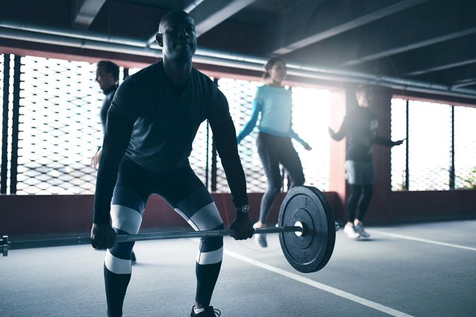 Man doing deadlifts with people skipping rope in background