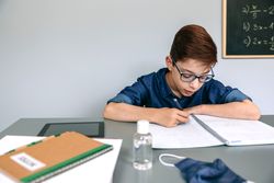 Boy writing in his notebook at school
