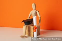 Wooden statuette of a man with a graduation hat and diploma. 0LdvJV
