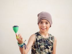 Smiling boy spinning tops on finger and looking at camera