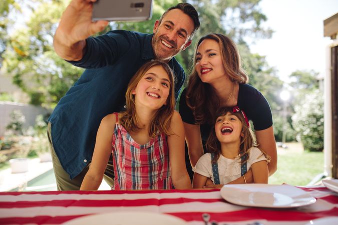 Smiling man taking a selfie with his family members using a mobile phone