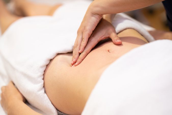 Physio massaging patient’s stomach