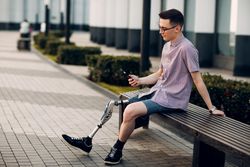 Man sitting on bench with prosthetic leg outdoor