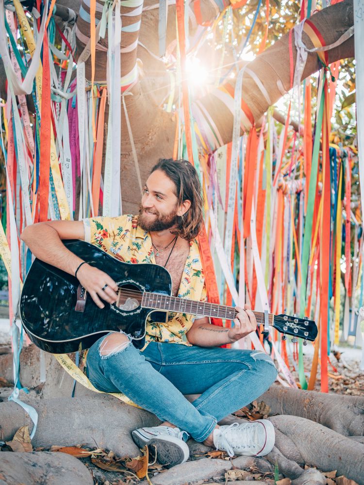 Man sitting under tree playing guitar